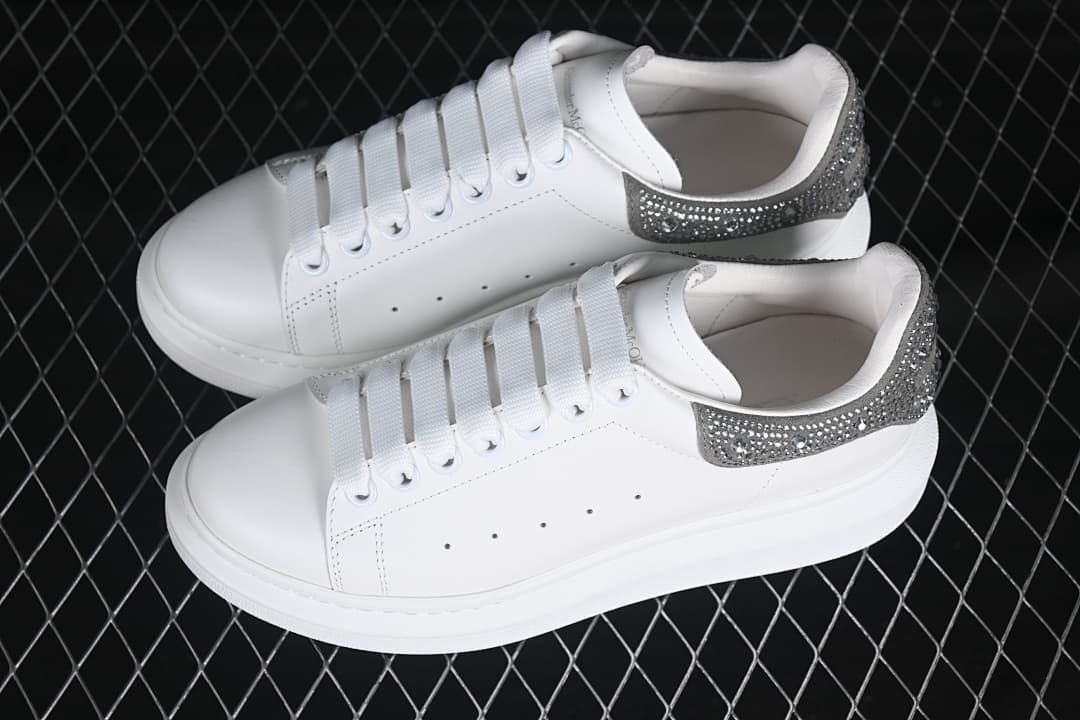 Pair of white low-top sneakers with silver-tone embellished heel panels.