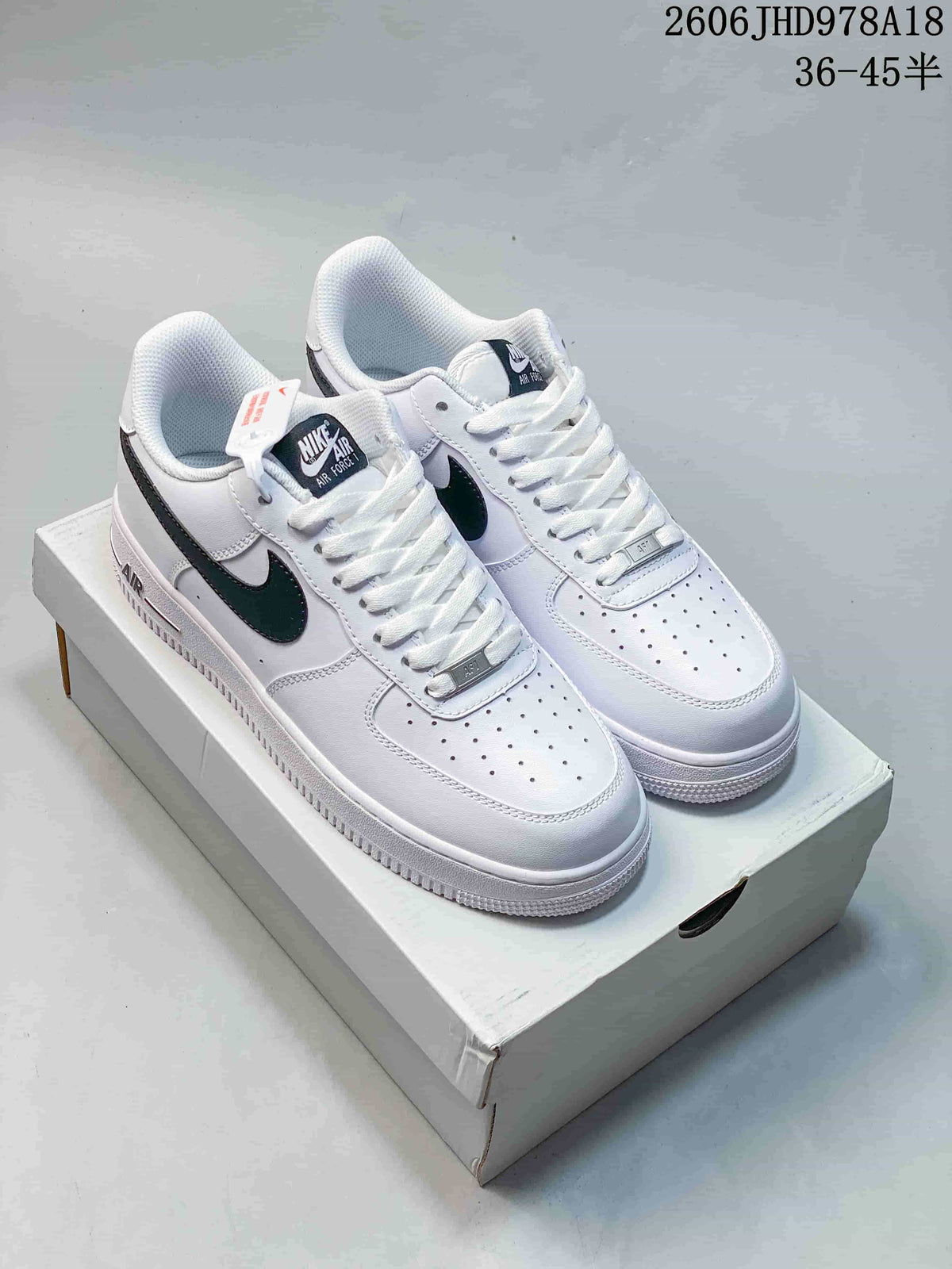Pair of white low-top Nike Air Force 1 sneakers with black Swooshes on a box.