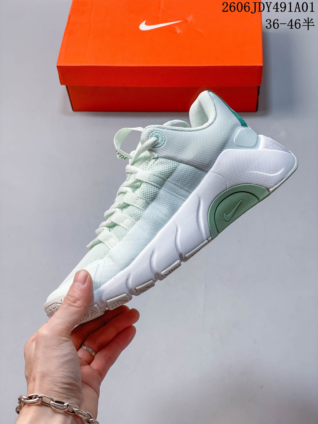 Side view of the white training shoe with green accents and a sculpted midsole.