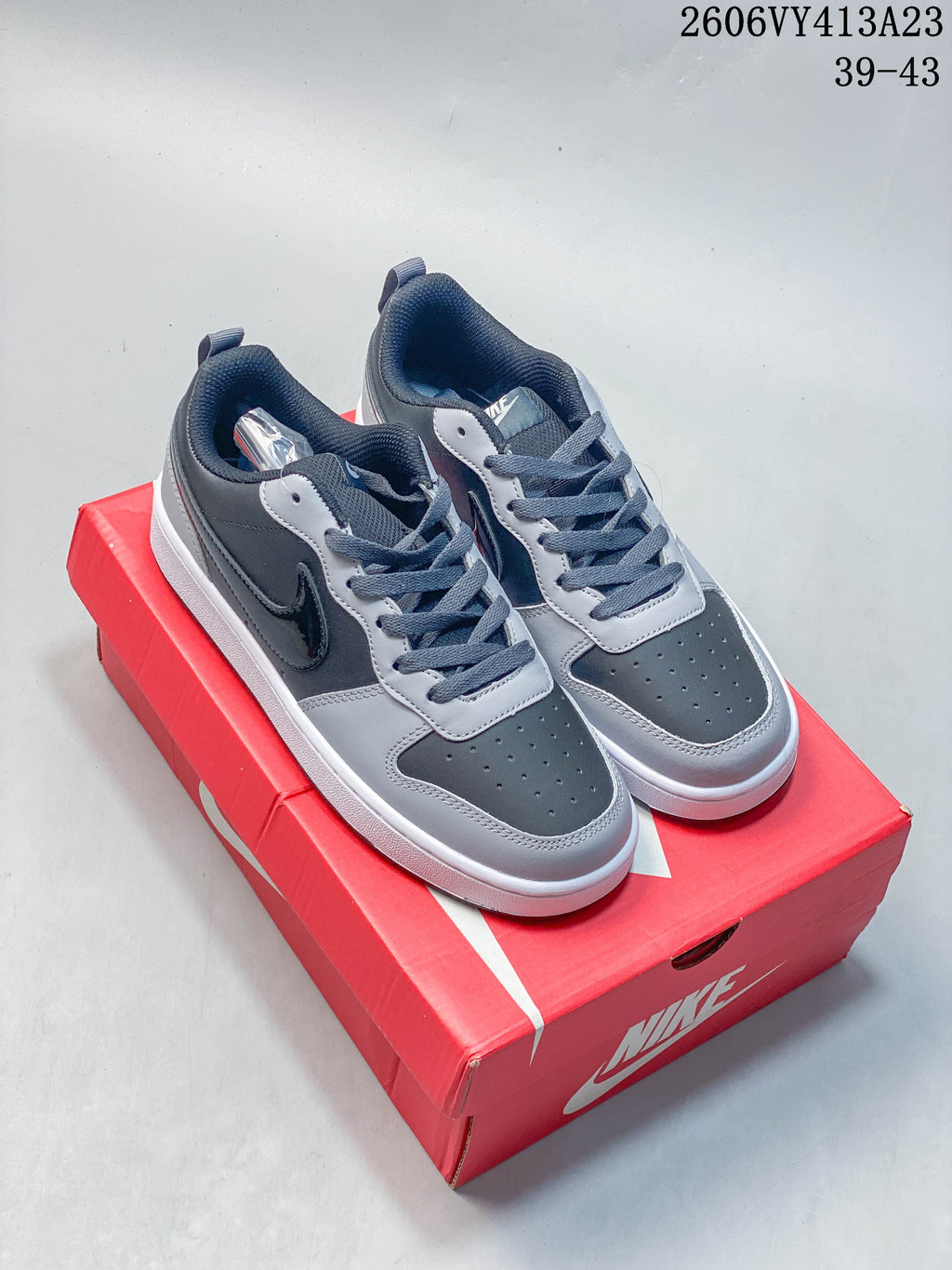 Pair of gray and black NikeCourt Borough 2 low-top sneakers on a red shoe box