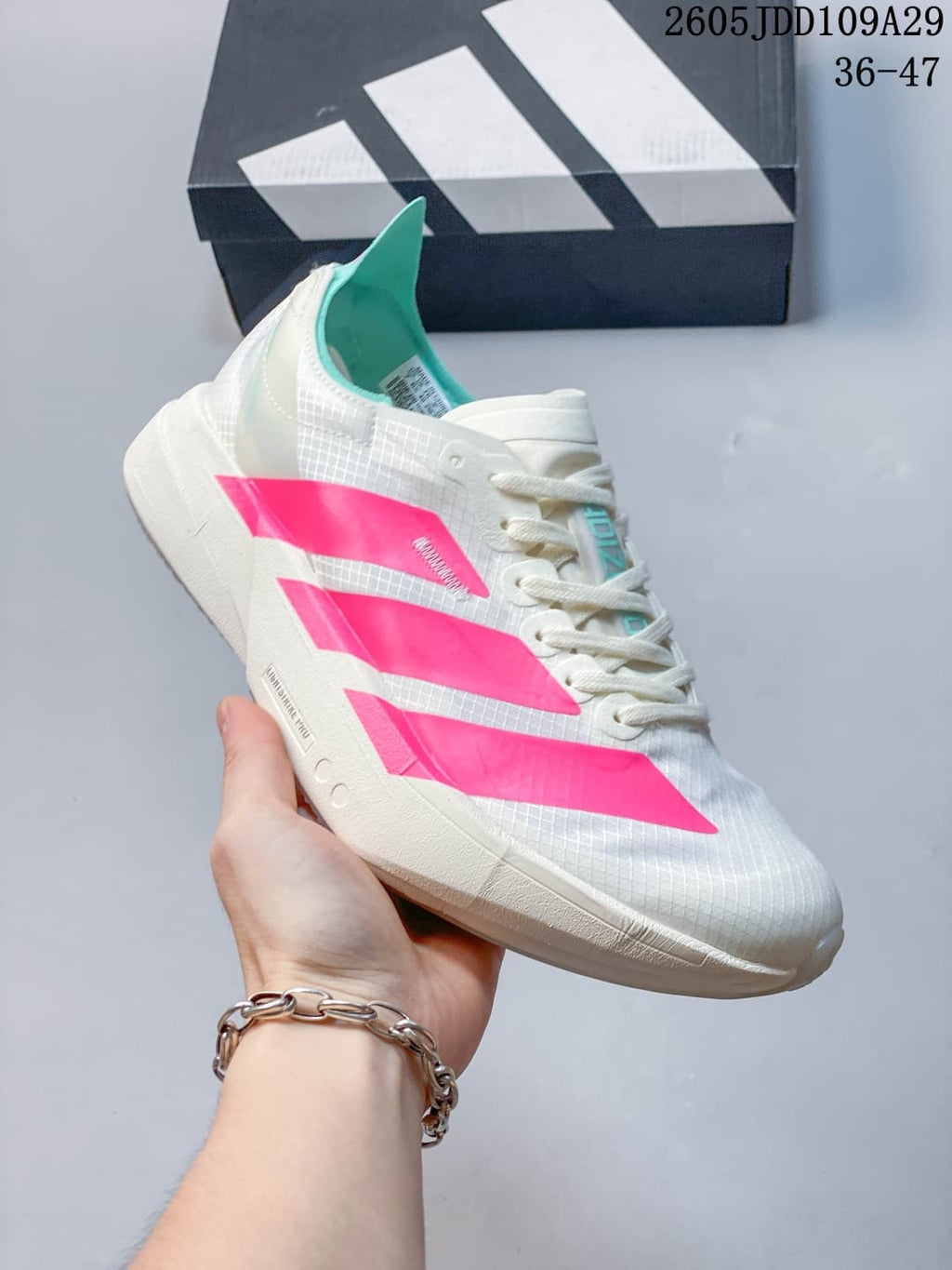 Angled side view showing the white patterned upper, bright pink detailing, lace-up construction, and sculpted sole.