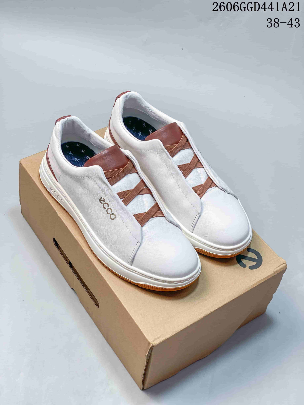 Pair of white ECCO sneakers with brown elastic straps and gum-colored soles, shown on a shoebox.