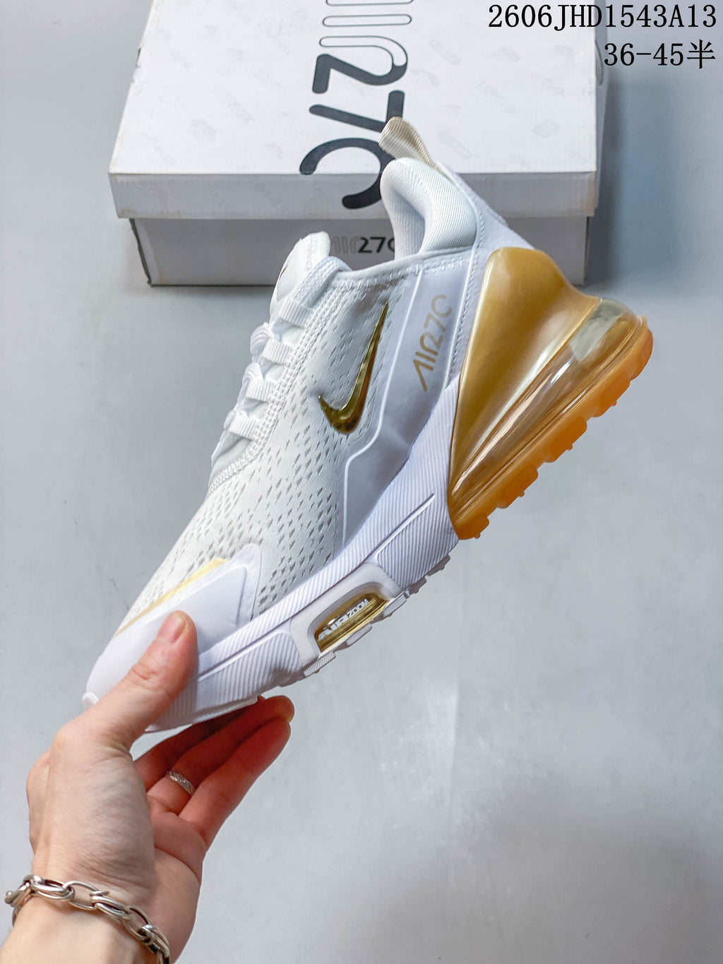 Side view of a white Nike Air Max 270 sneaker with gold-colored accents