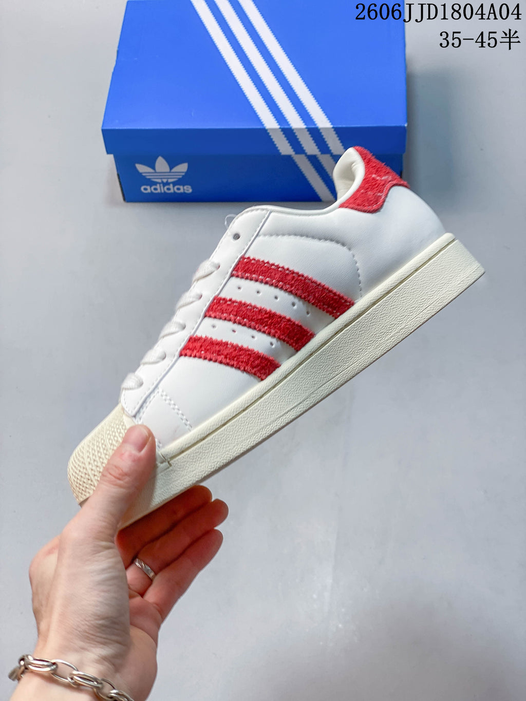 Side view of the white low-top sneaker with red stripes and an off-white sole.