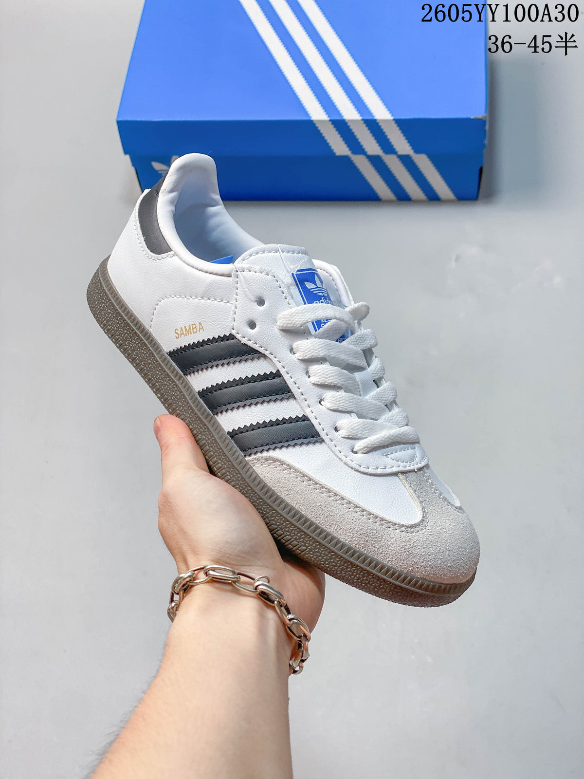 Side view of a white Adidas Samba sneaker with dark stripes and a gum-look outsole