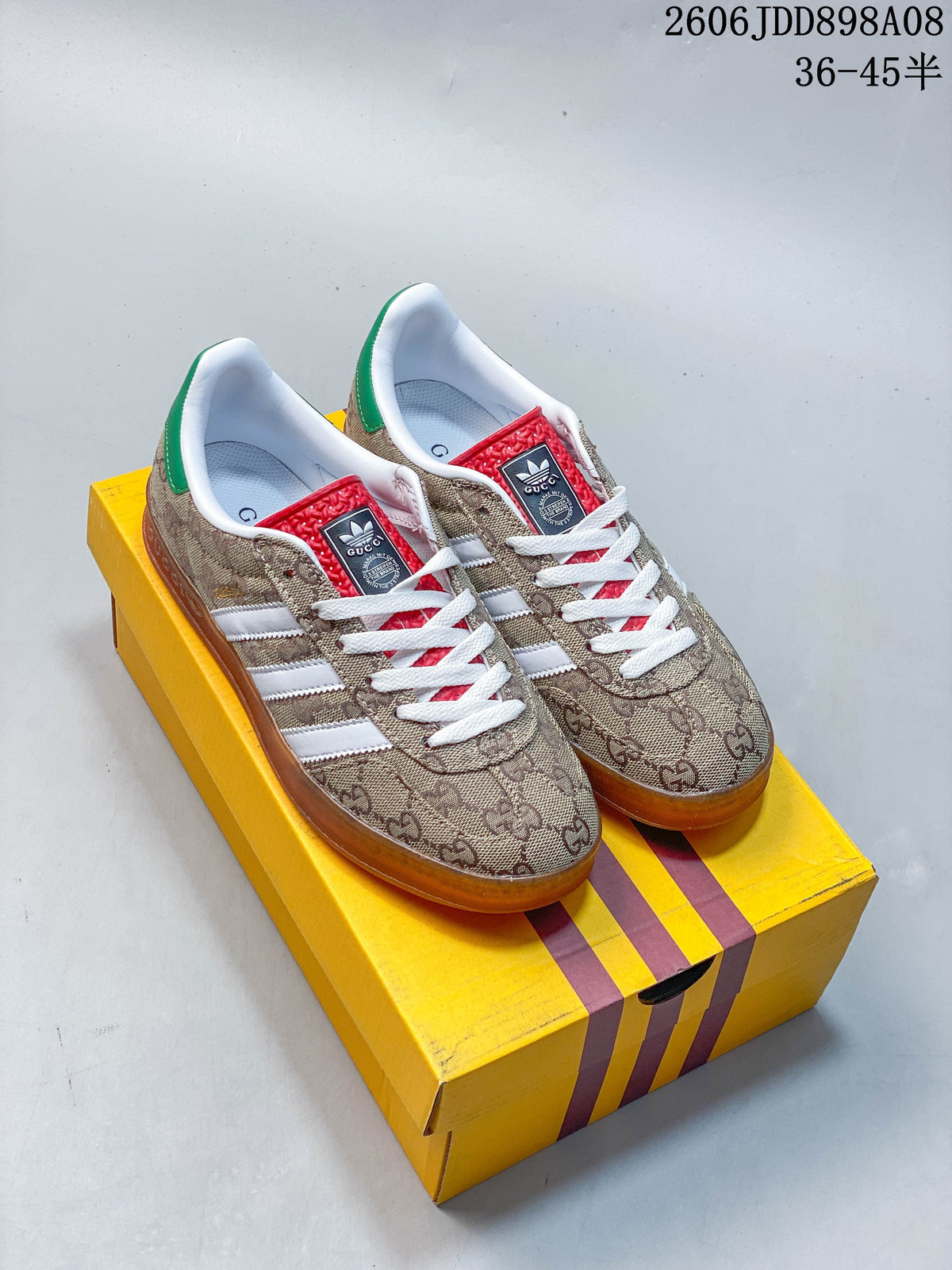 Beige patterned sneakers with white stripes, red tongue accents, and amber-toned outsoles