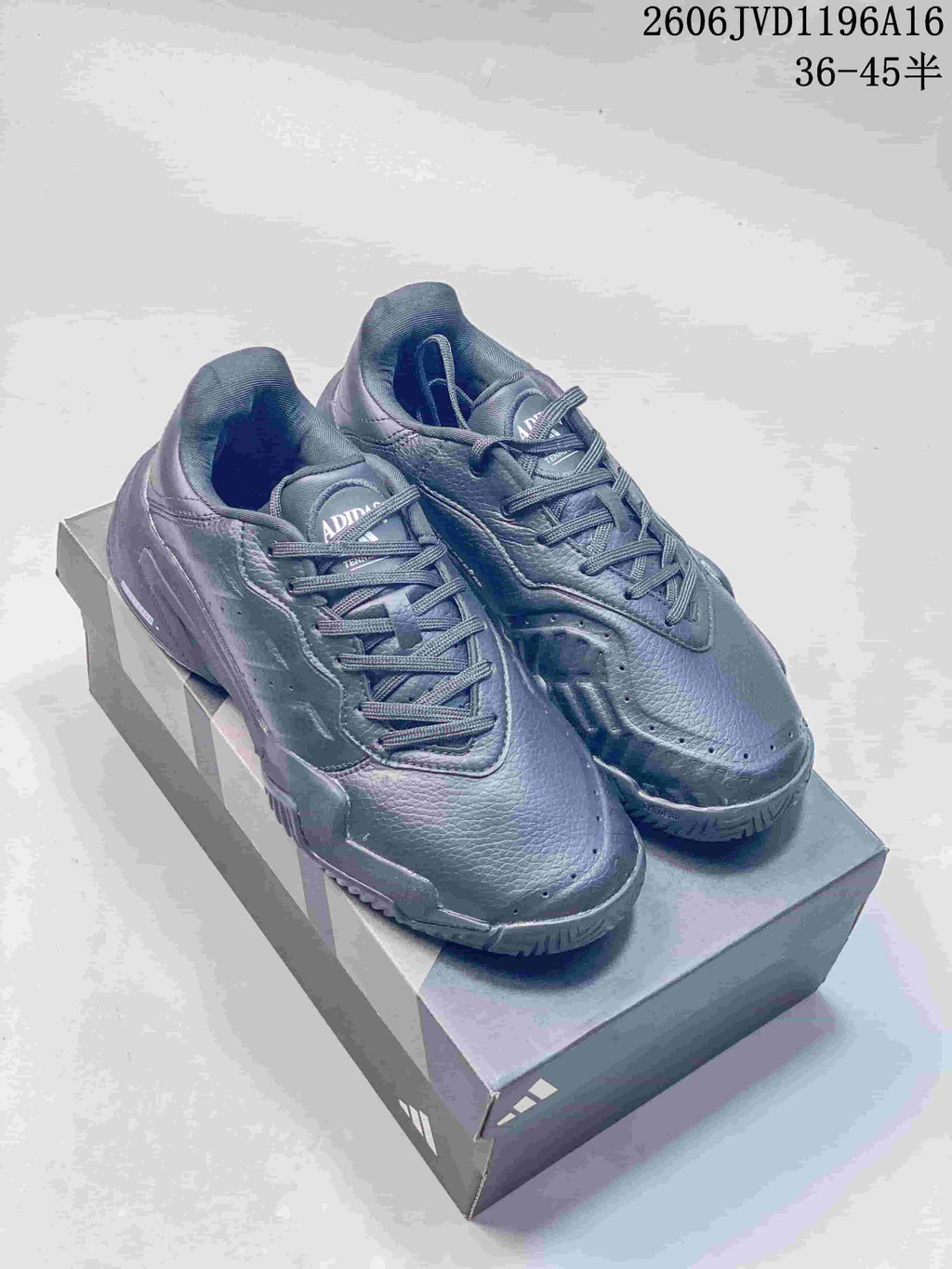 Pair of dark grey Adidas Barricade tennis shoes on a shoebox
