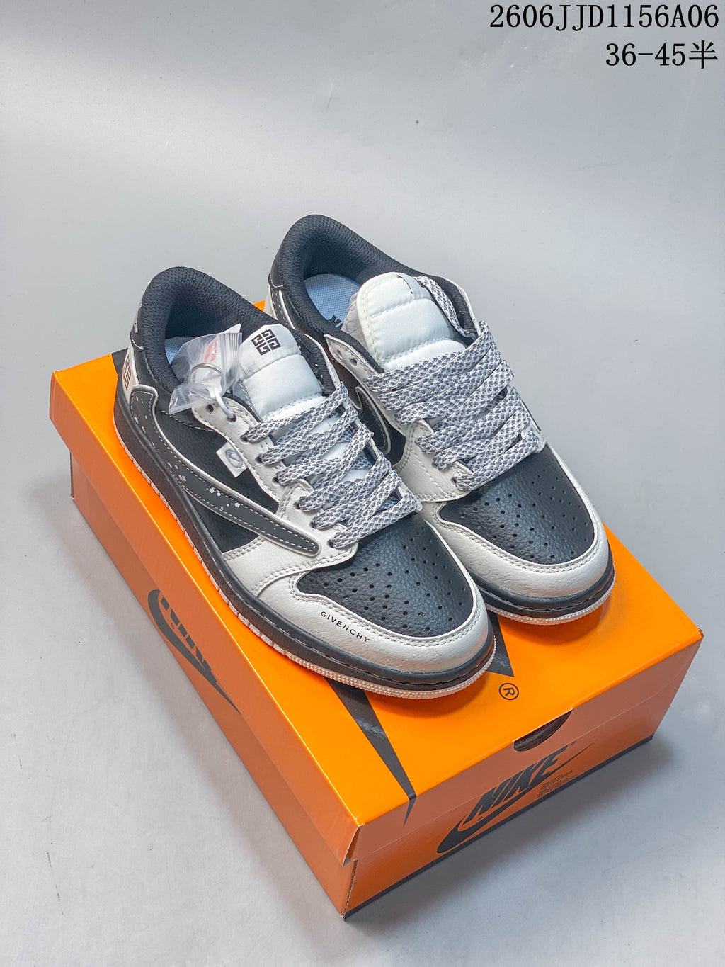 Pair of gray and white low-top sneakers displayed on an orange shoebox