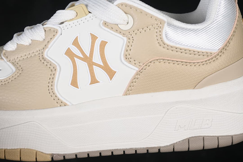 Close-up of the Yankees logo, beige panels, and chunky midsole