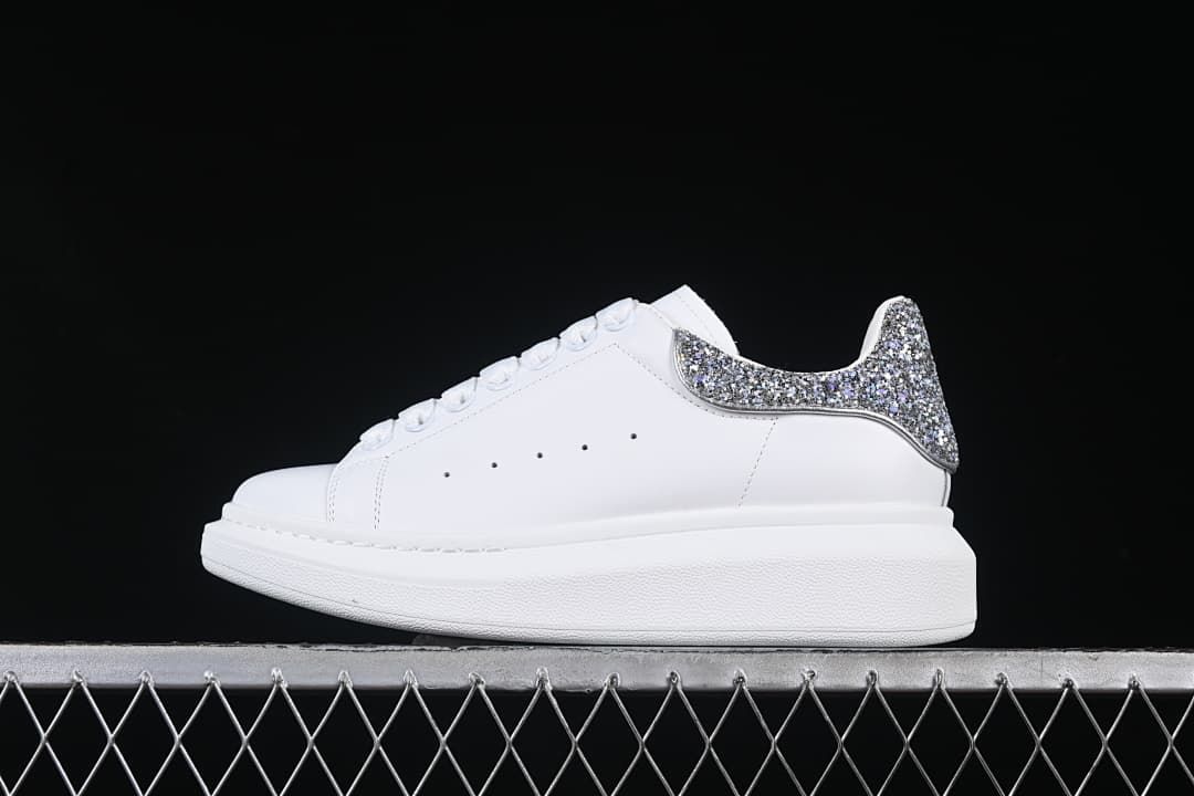 Side profile of a white sneaker with a silver-tone glitter heel panel.