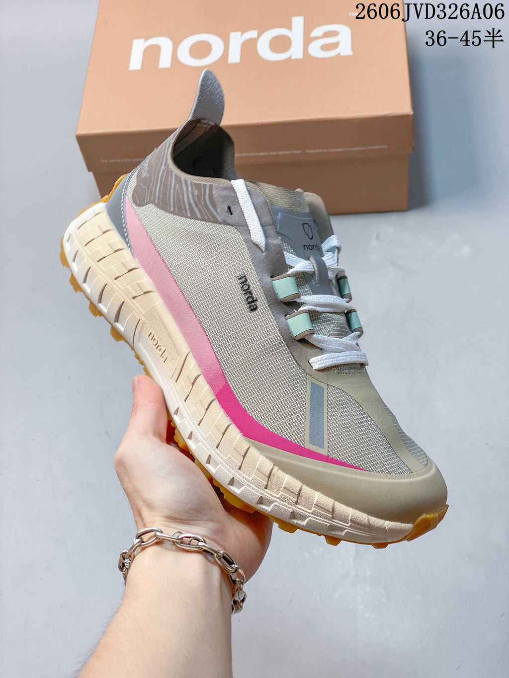 Angled side view of the taupe sneaker with pink accents and pull tab.