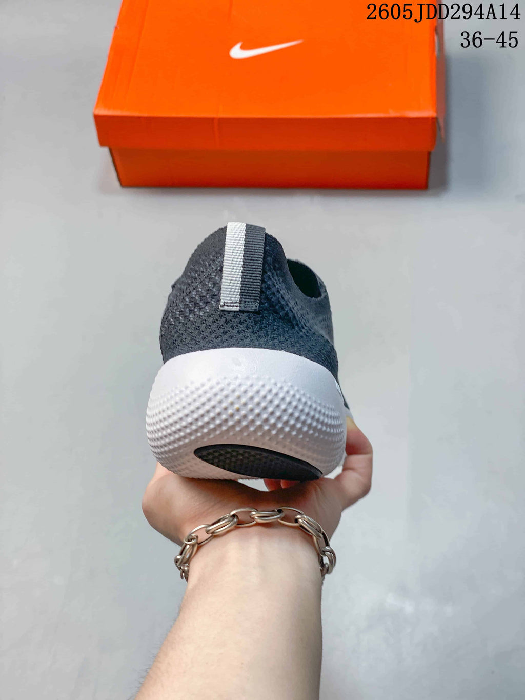 Rear view of a charcoal Nike Free shoe with a white heel sole and pull tab