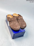 Pair of brown closed-toe buckle mules displayed on a Birkenstock-branded box