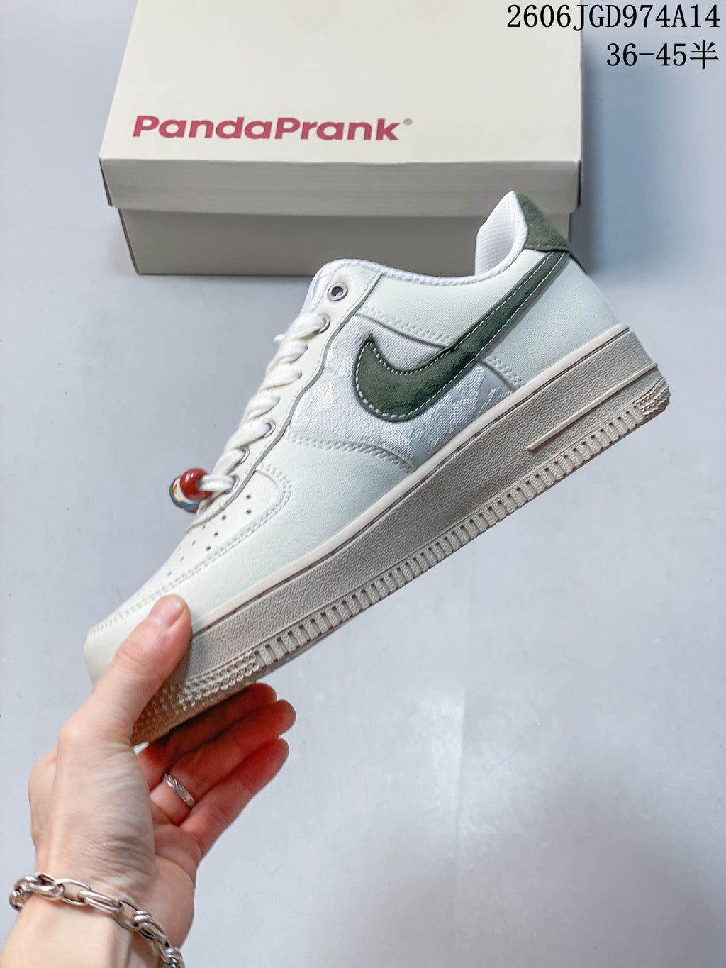 Side view of a white low-top sneaker with a dark green side accent and raised beige-toned sole