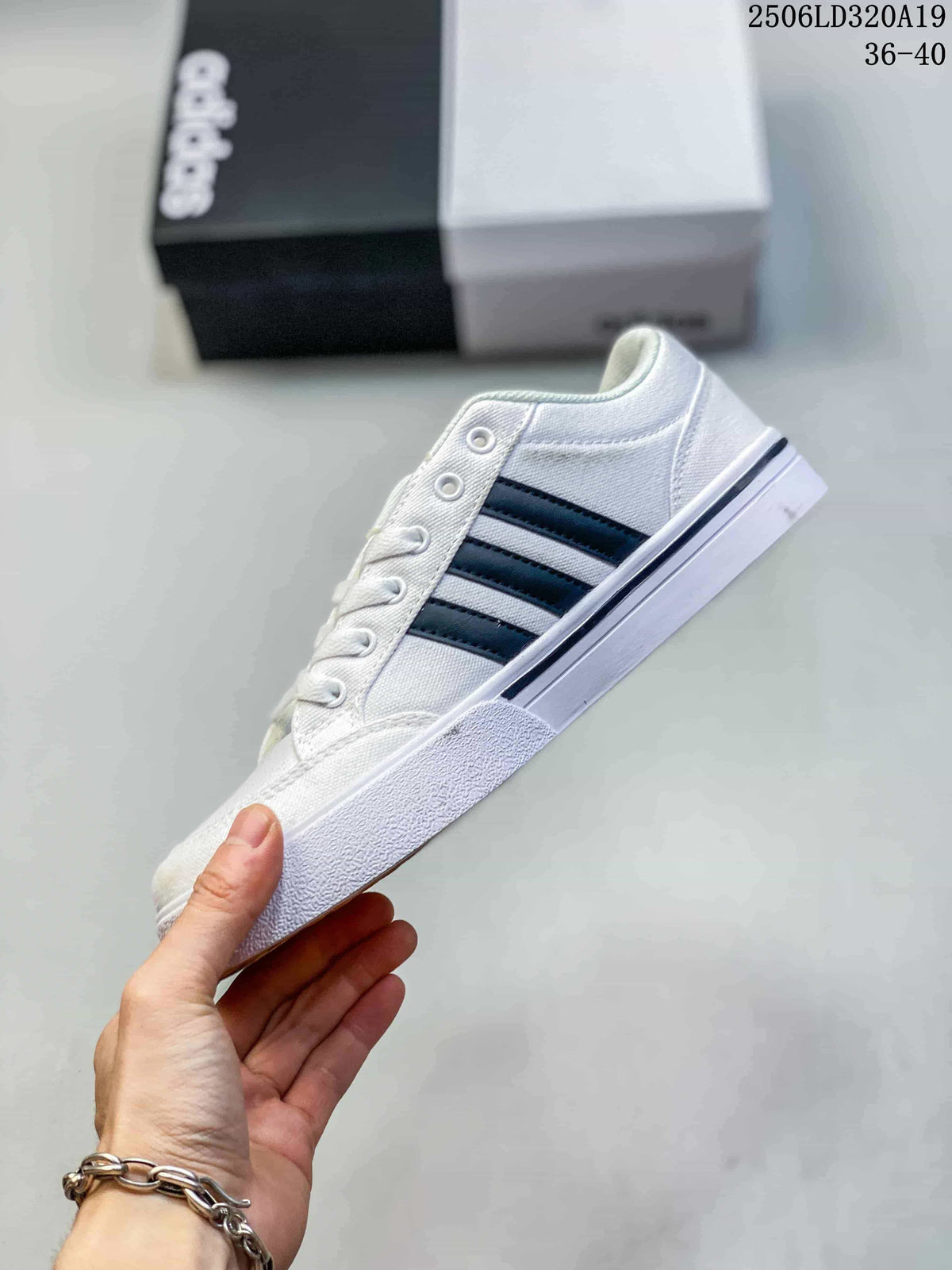 Side view of the white low-top sneaker with black stripes and a flat sole.