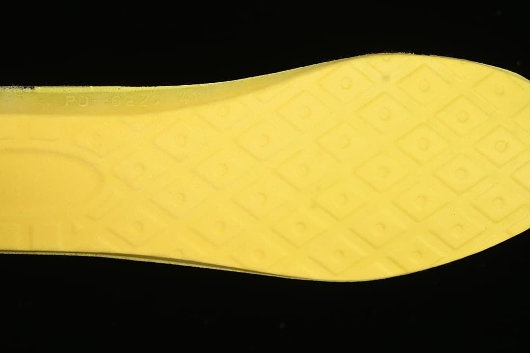Close-up of the yellow outsole with a geometric tread pattern