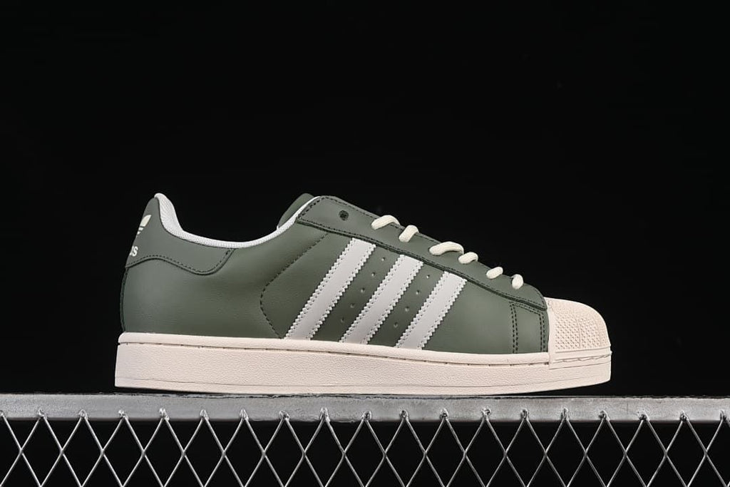 Side profile of the green sneaker with white stripes and a cream shell toe.
