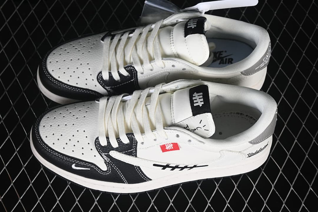 Pair of off-white, black, and grey low-top sneakers shown from above, with perforated toe panels and graphic side details.