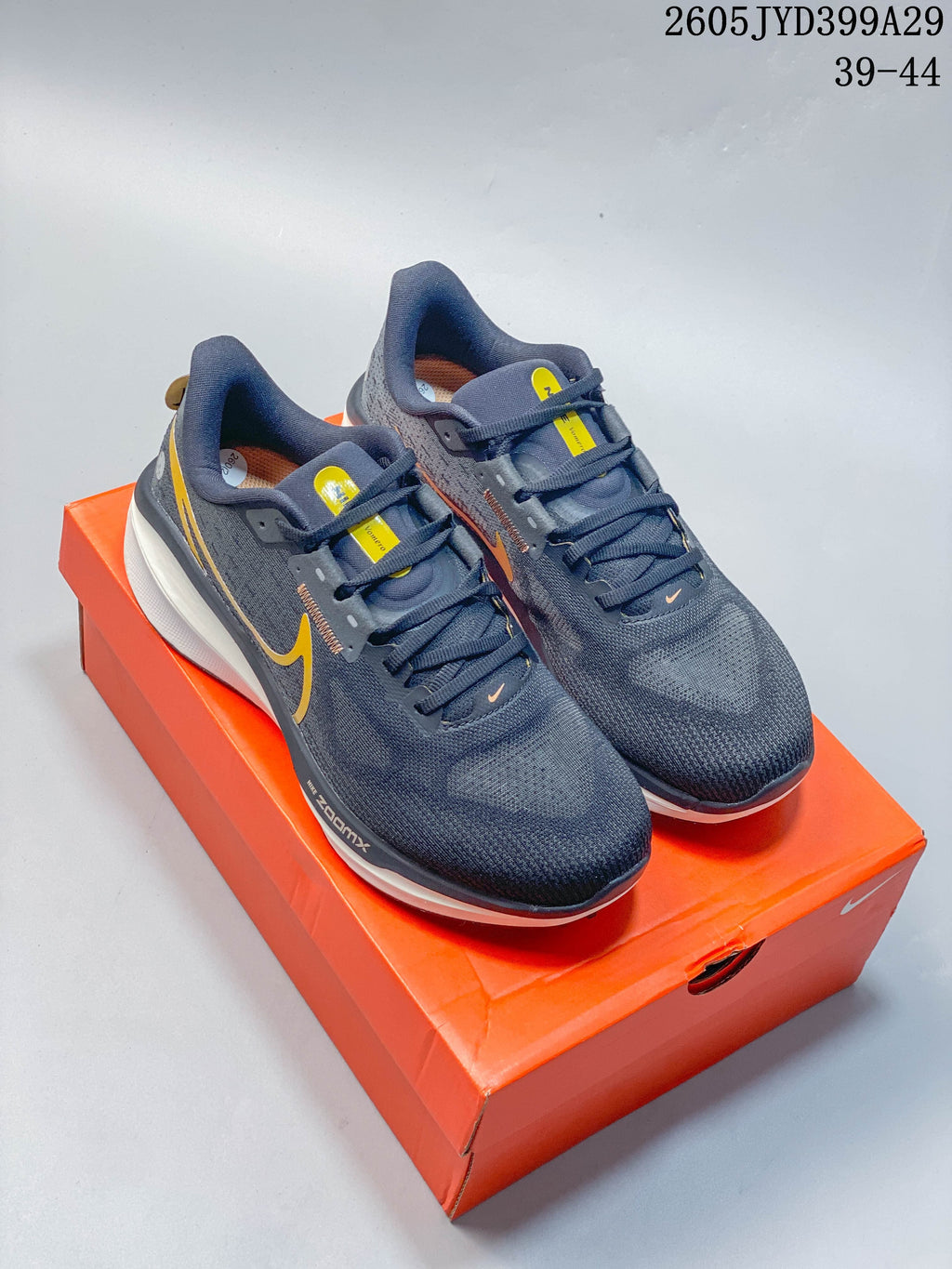 Pair of dark gray Nike Air Zoom Vomero 17 shoes with yellow accents on an orange shoebox.