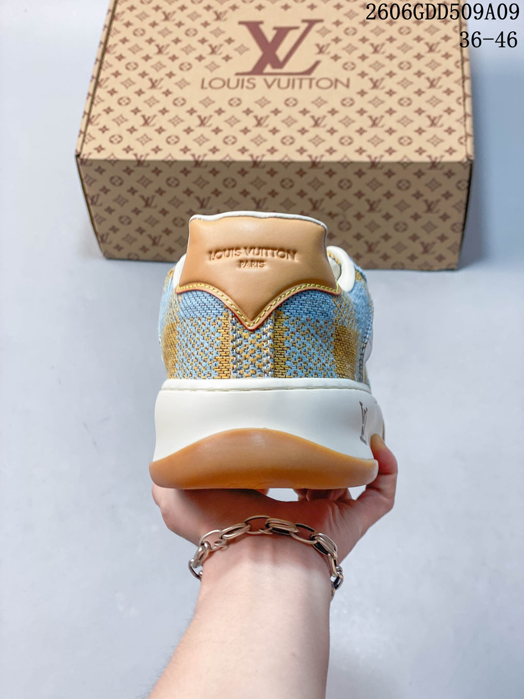 Rear view of blue and tan check-patterned sneaker with tan heel panel and white midsole.