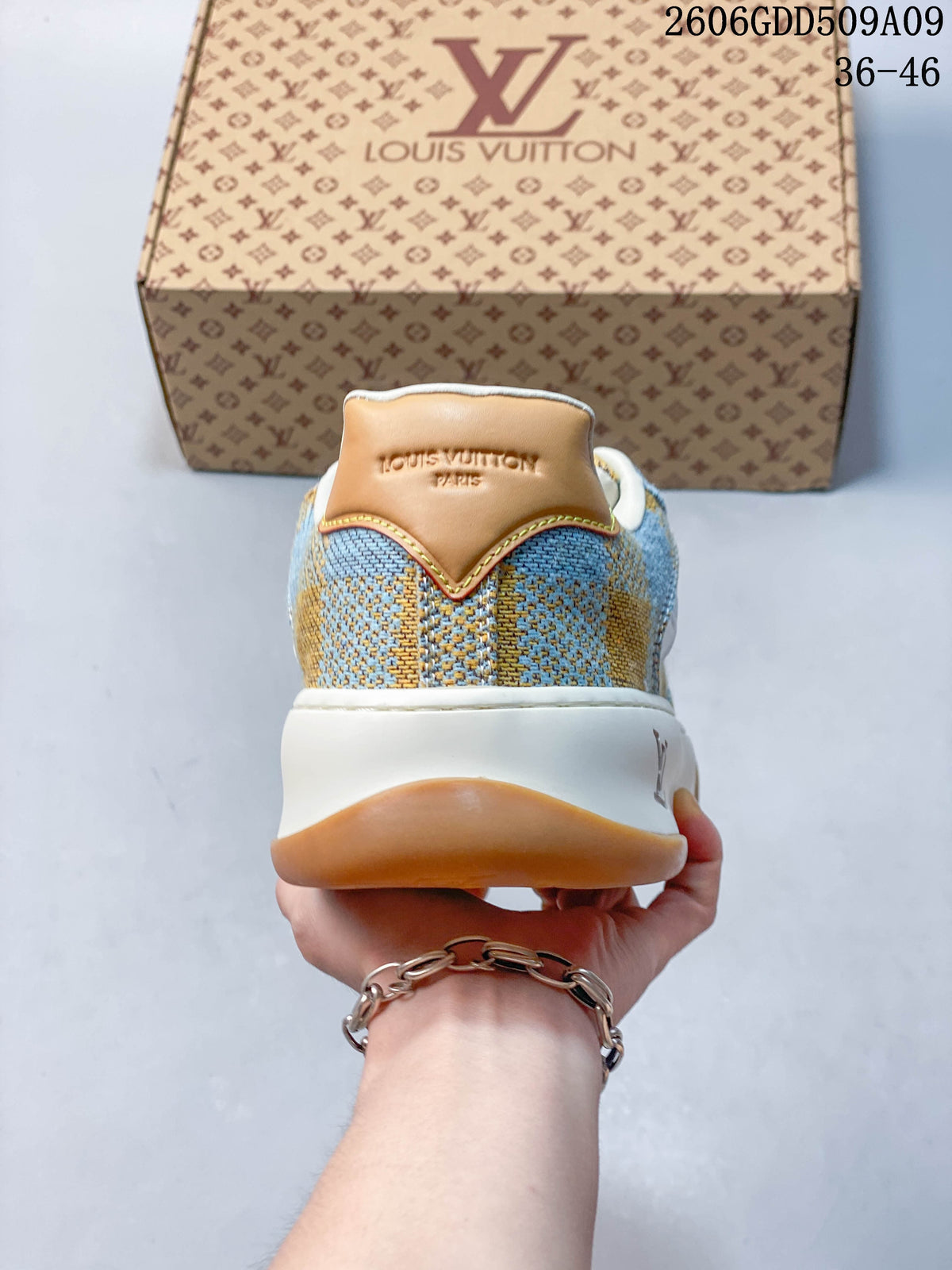 Rear view of blue and tan check-patterned sneaker with tan heel panel and white midsole.