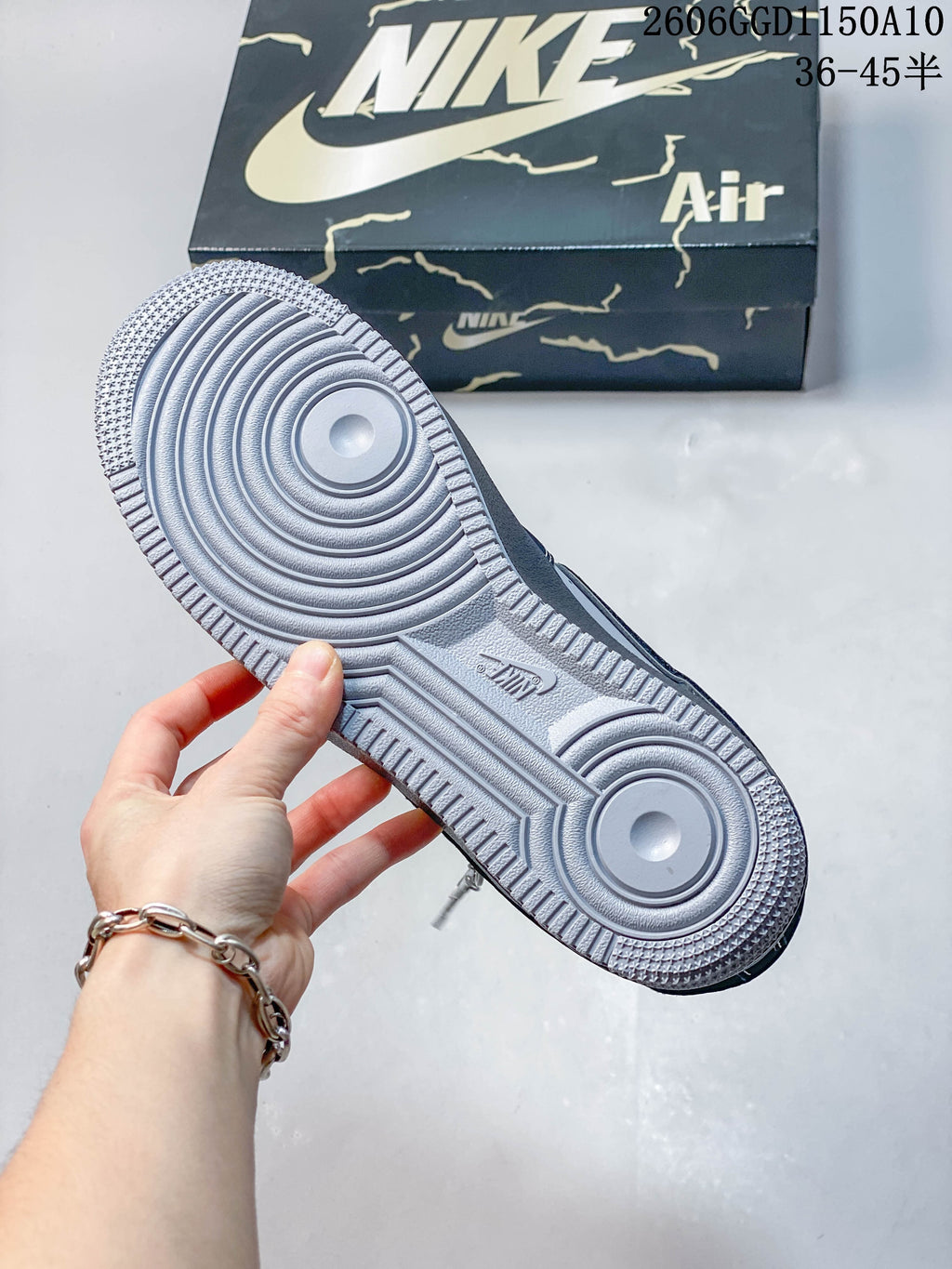 Close-up of the patterned outsole on a navy and gray sneaker beside its box