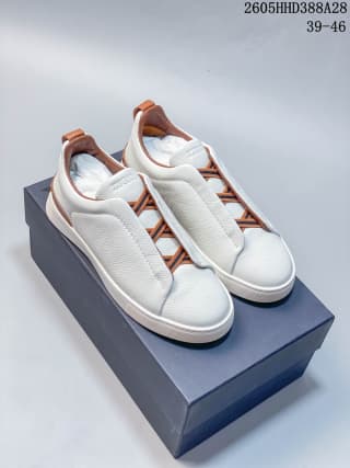 Pair of white and tan low-top sneakers displayed on a box.