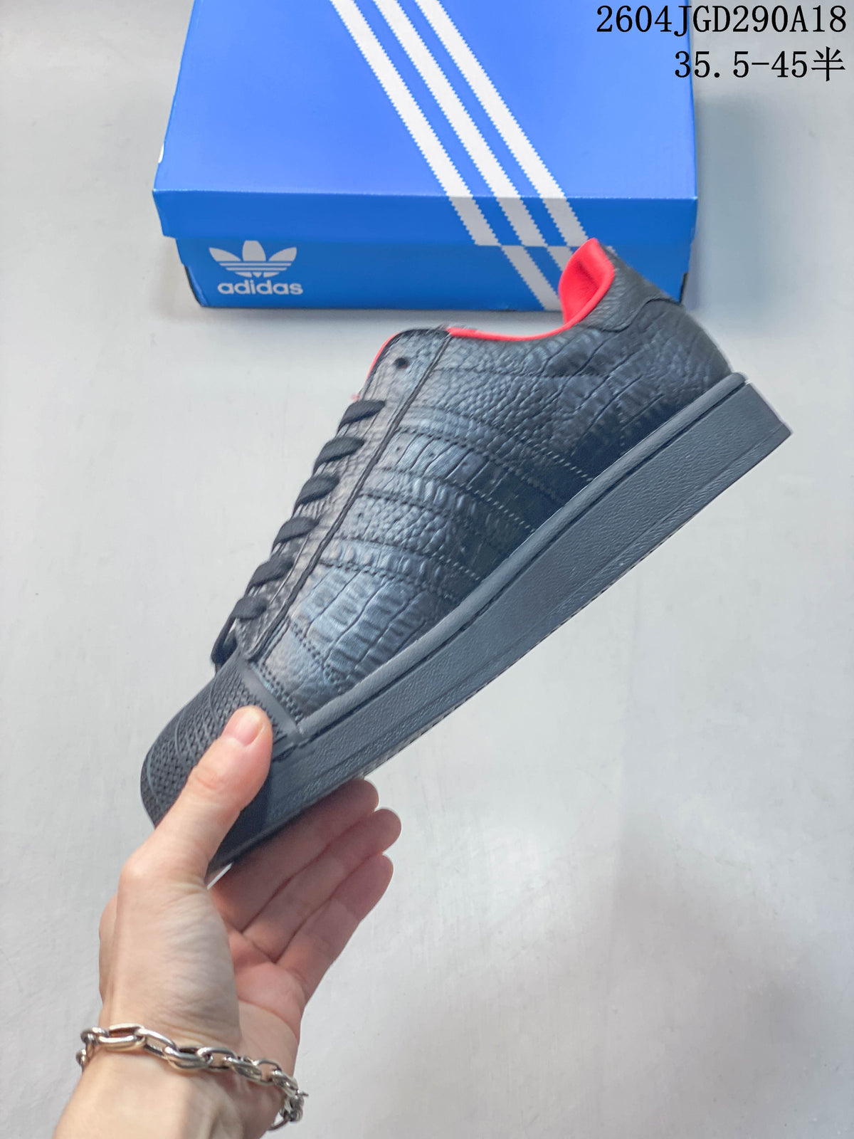Side view of the black textured Superstar 2 sneaker with red lining and a tonal sole.