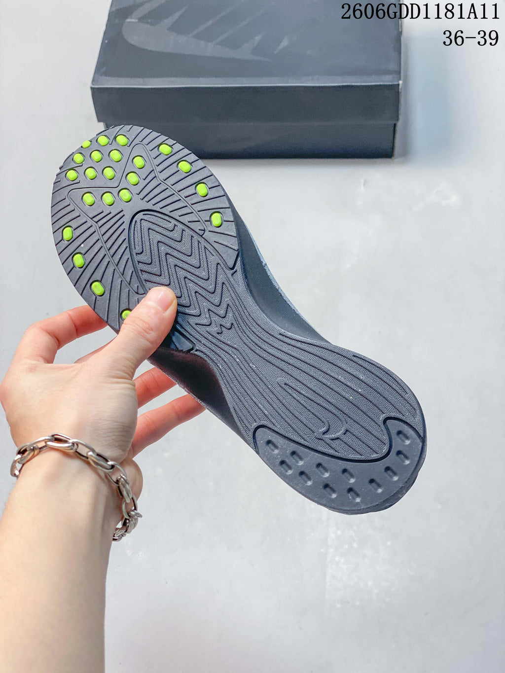 Underside of the sneaker showing a dark outsole with bright lime-colored details.
