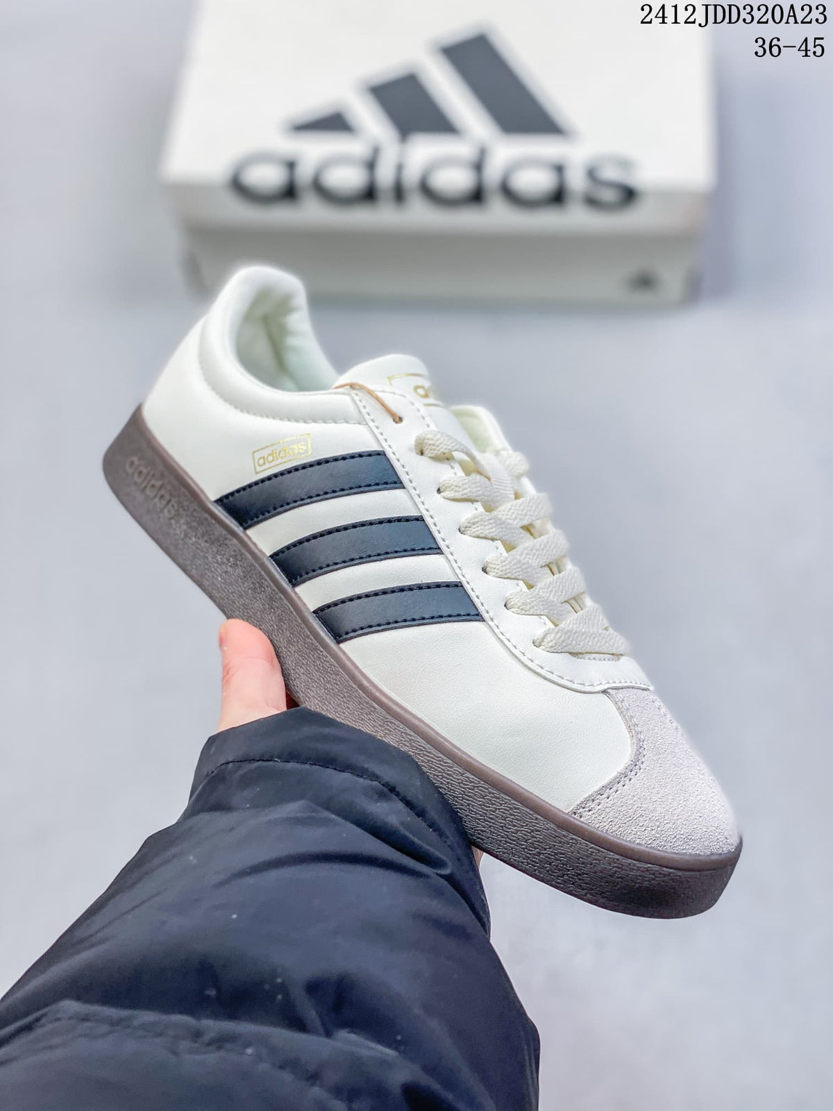 Angled side view of the white sneaker with dark stripes and a gray toe panel.