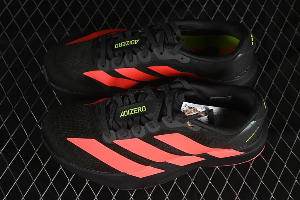 Pair of black running shoes with coral-red stripes and lime accents