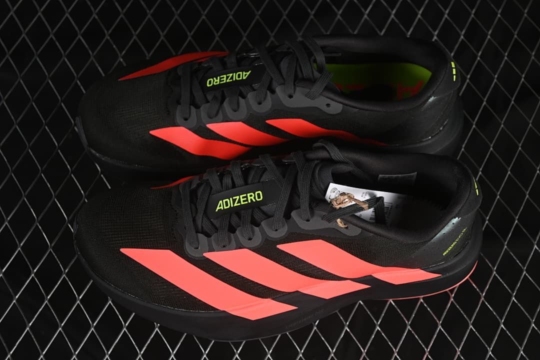 Pair of black running shoes with coral-red stripes and lime accents