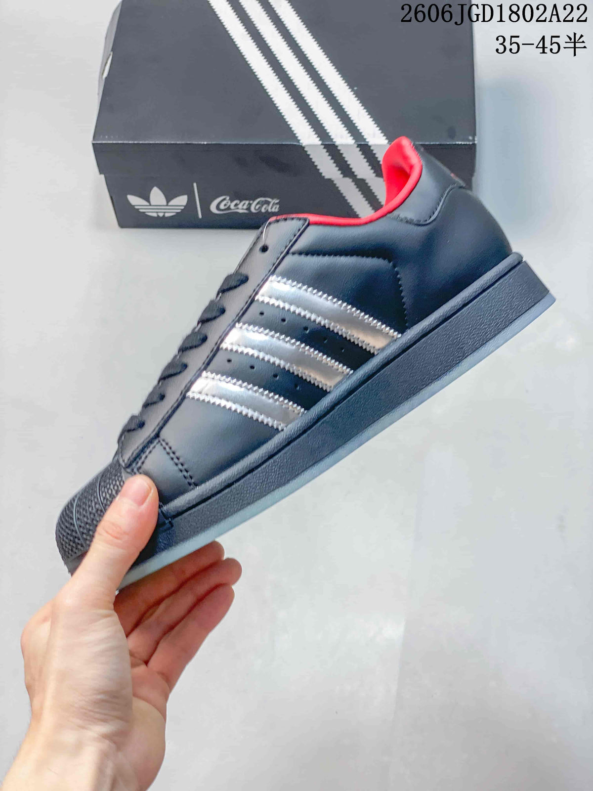 Side view of the low-top sneaker with metallic silver stripes, red collar detail, and textured shell toe.