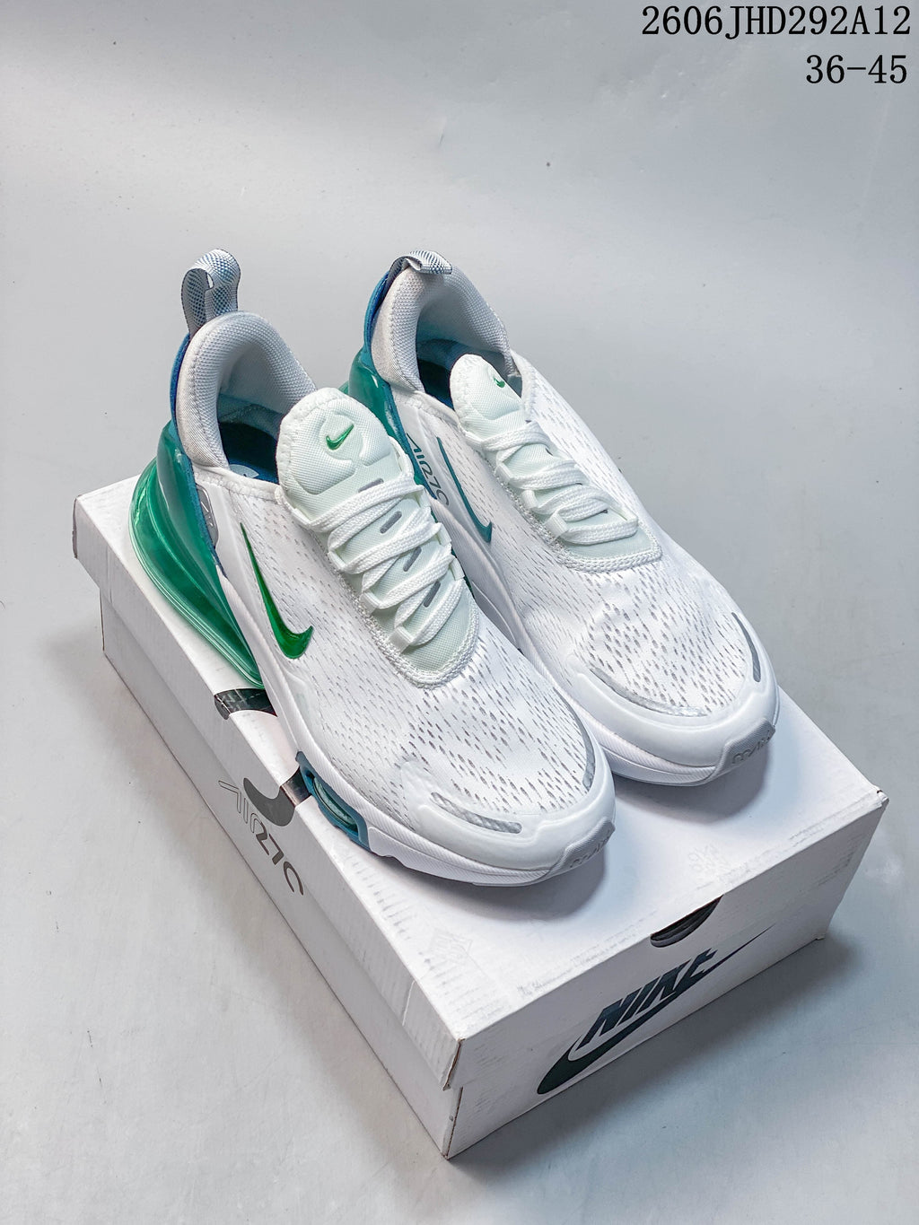 Pair of white Nike Air Max 270 sneakers with green and blue accents on a shoe box