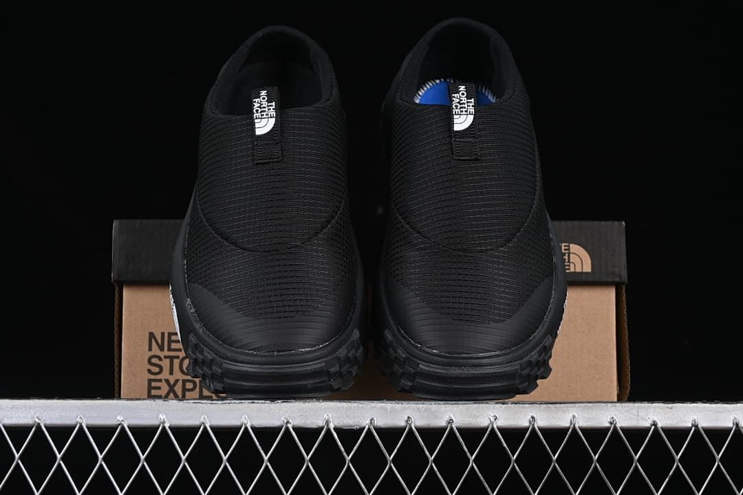 Front view of the pair of black slip-on mules on the box