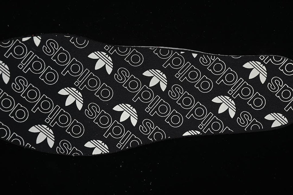 Removable insole shown with a black-and-white adidas Trefoil pattern.