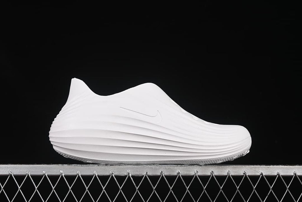 Side profile of the white clog showing its ridged sole and upper