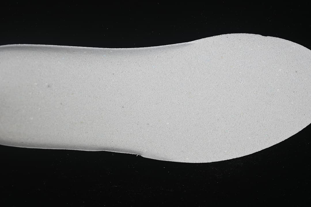 Close view of a pale shoe-shaped component against a dark background.