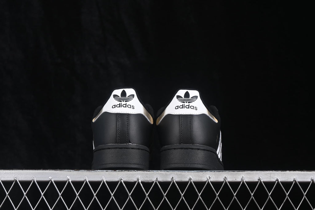 Rear view of the sneakers showing white adidas heel tabs and black uppers.