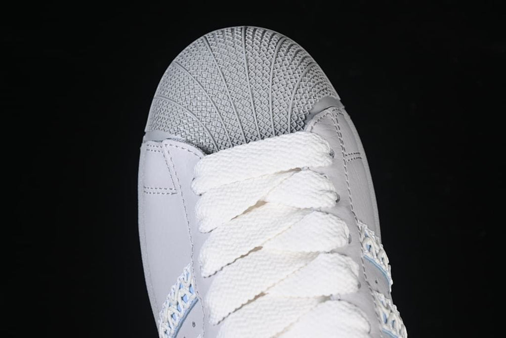 Top-down close-up of the textured shell toe and broad white laces.
