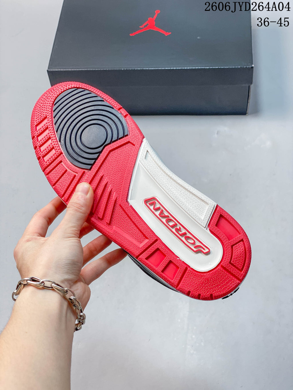 Underside of the sneaker showing a red and white outsole with dark circular tread section
