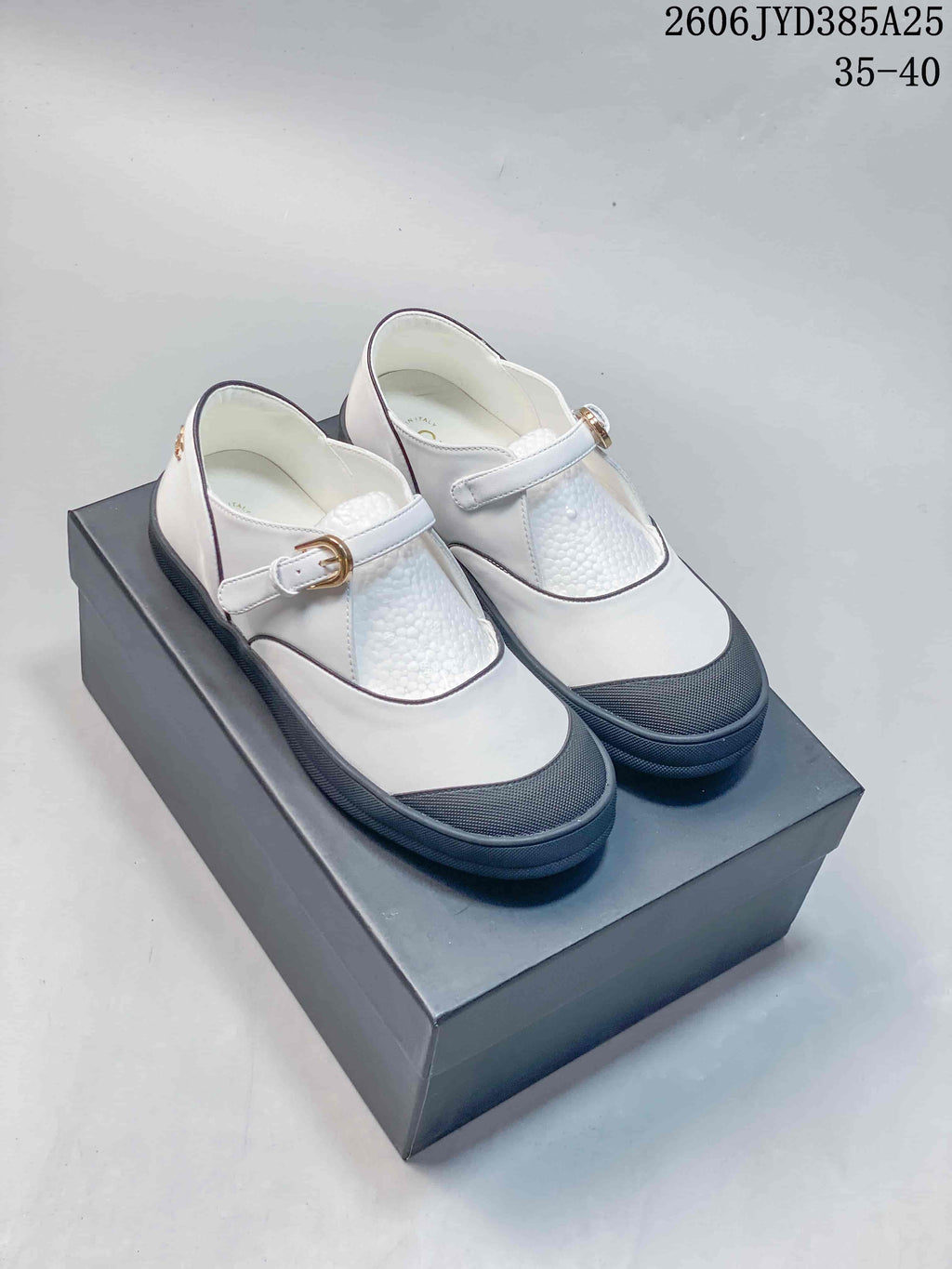 White Mary Jane flats with dark trim, textured dark toe caps, and buckle straps; size range 35–40 shown.