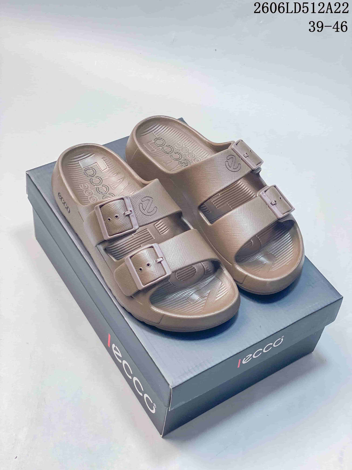 Pair of taupe ECCO double-buckle slide sandals shown on a box.