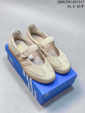 Pair of cream Adidas Originals-style Mary Jane sneakers with textured panels and gum soles, shown on a blue box