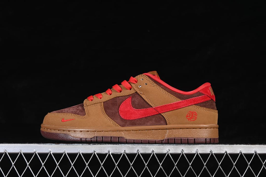 Side view of a brown Nike SB Dunk Low sneaker with red Swoosh and red accents