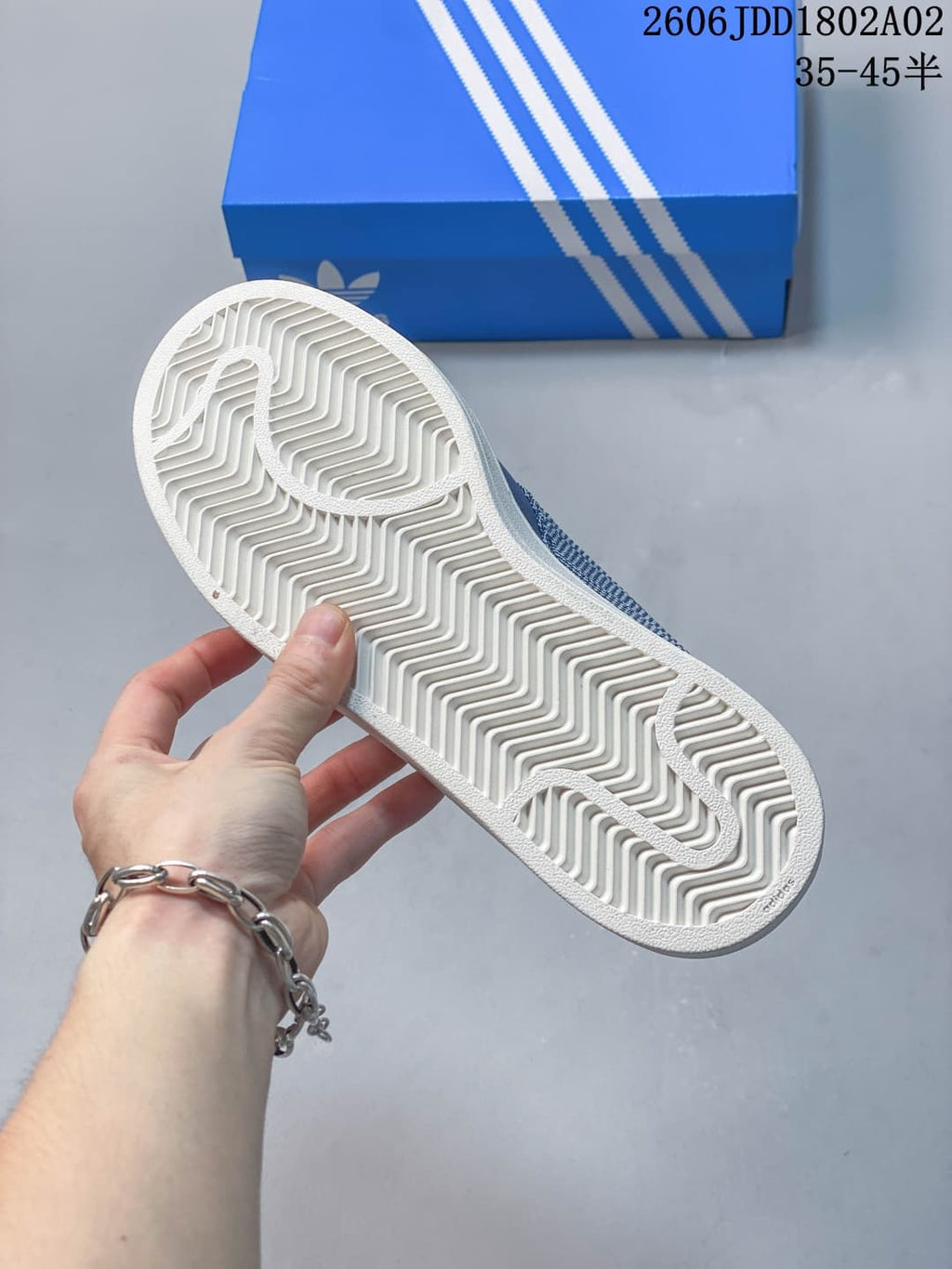Underside of the sneaker showing the white outsole with a repeating herringbone-style tread pattern and molded branding details.