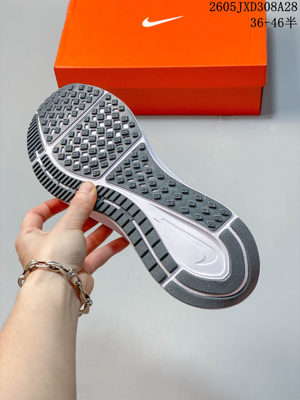 Close-up of the patterned outsole of a gray Nike running shoe.