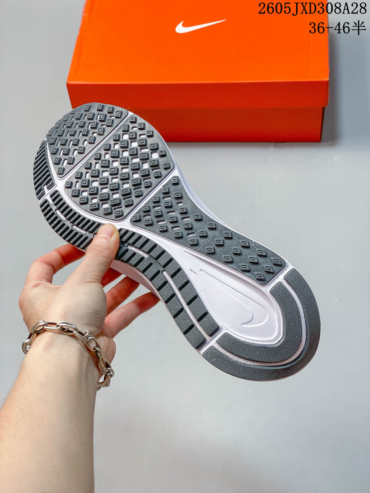 Close-up of the patterned outsole of a gray Nike running shoe.