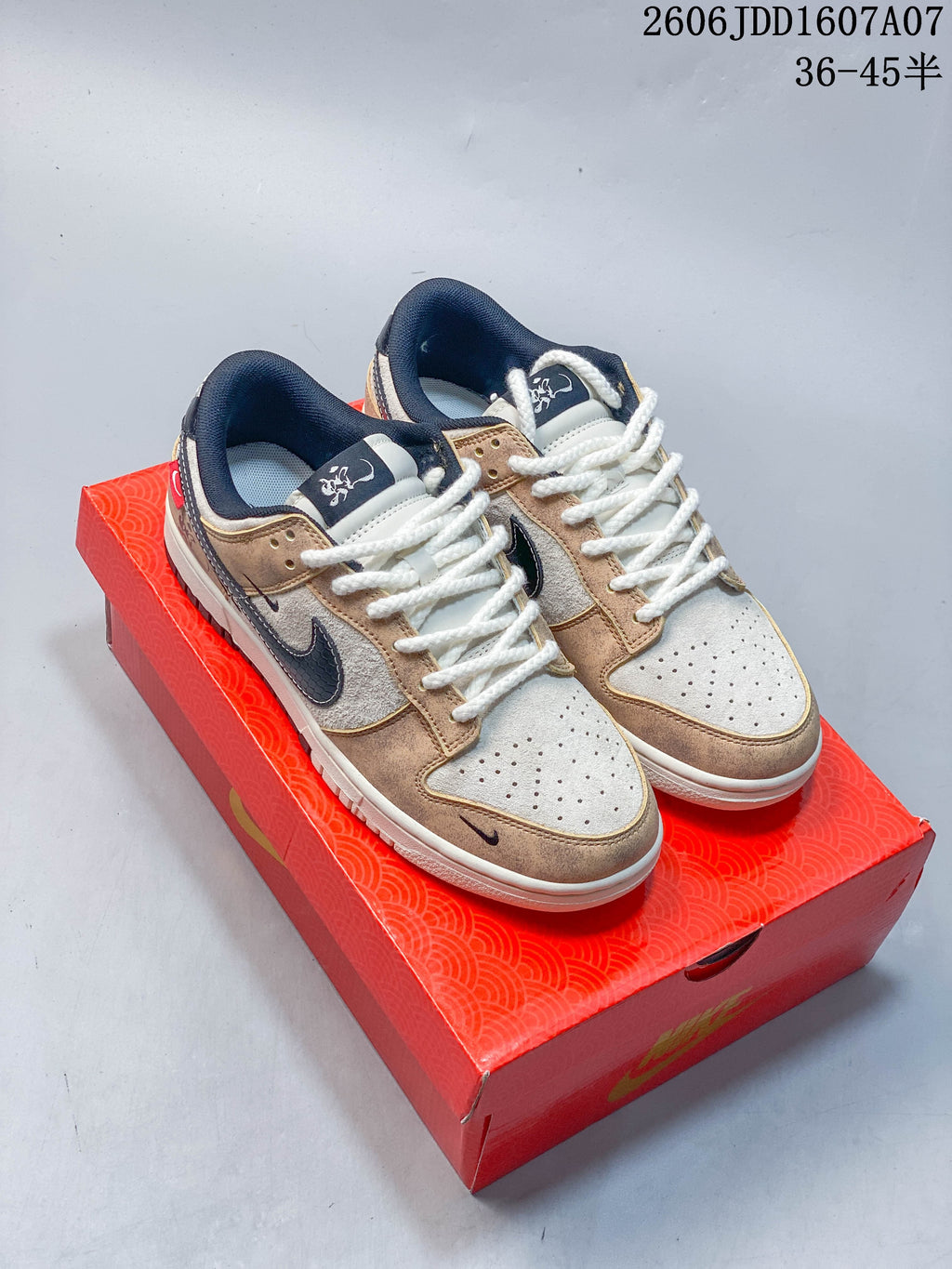 Pair of beige, cream, and navy Nike SB Dunk Low sneakers displayed on a red box; image overlay states sizes 36–45.5.