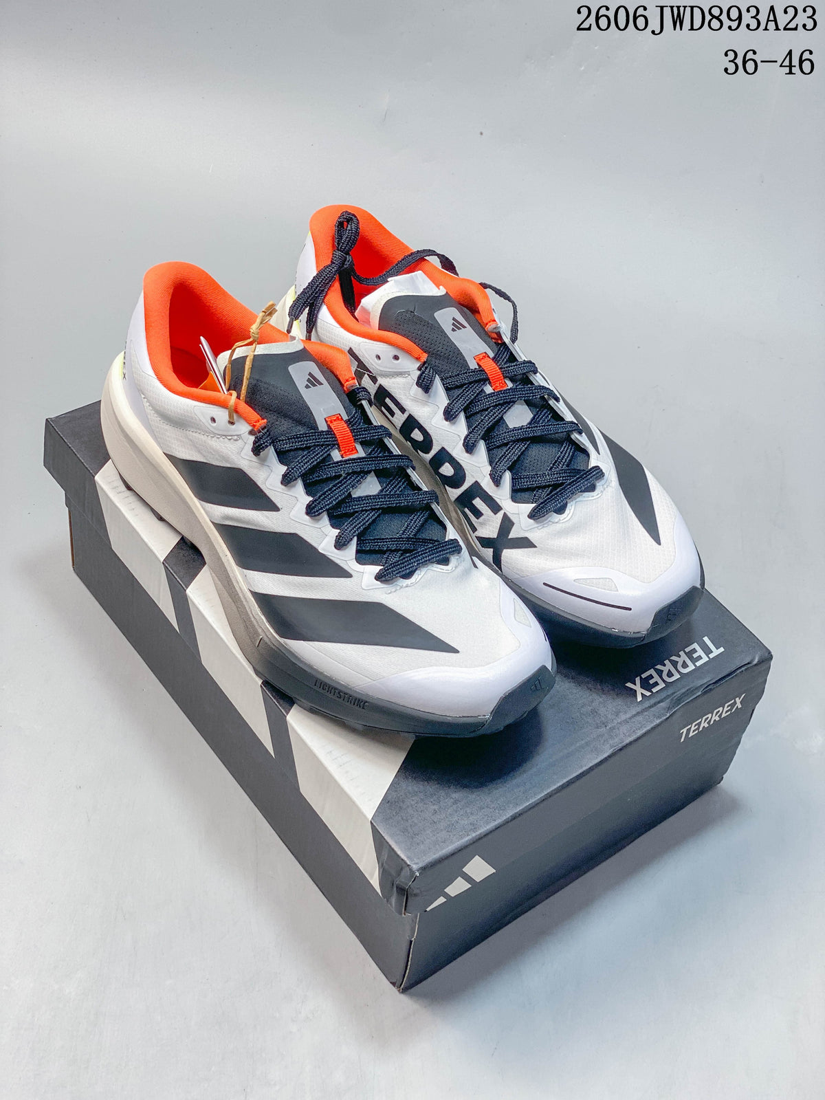 Pair of white adidas Terrex Agravic 4 trail running shoes with dark gray accents and orange collars.